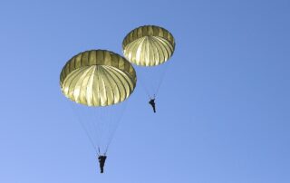 Zwei Fallschirmspringer mit geöffnetem Schirm am Himmel